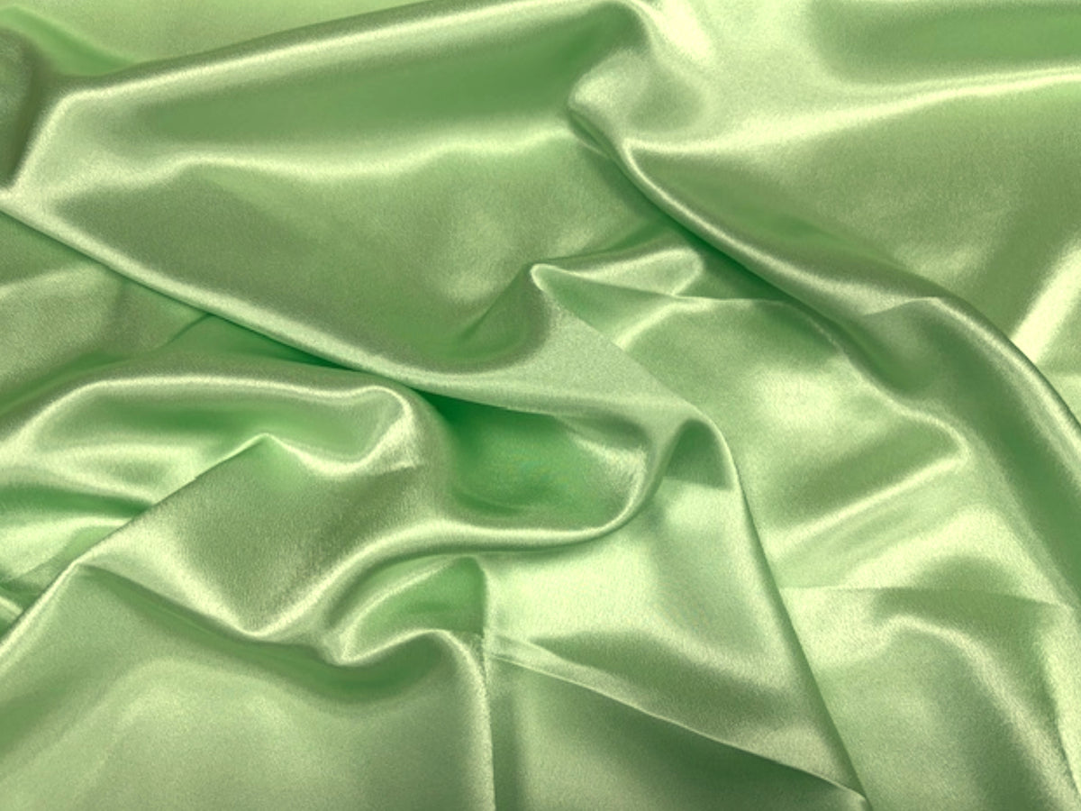 Apple green crepe-backed satin fabric from Cheap Fabrics, showcasing smooth satin surface with a textured crepe backing.