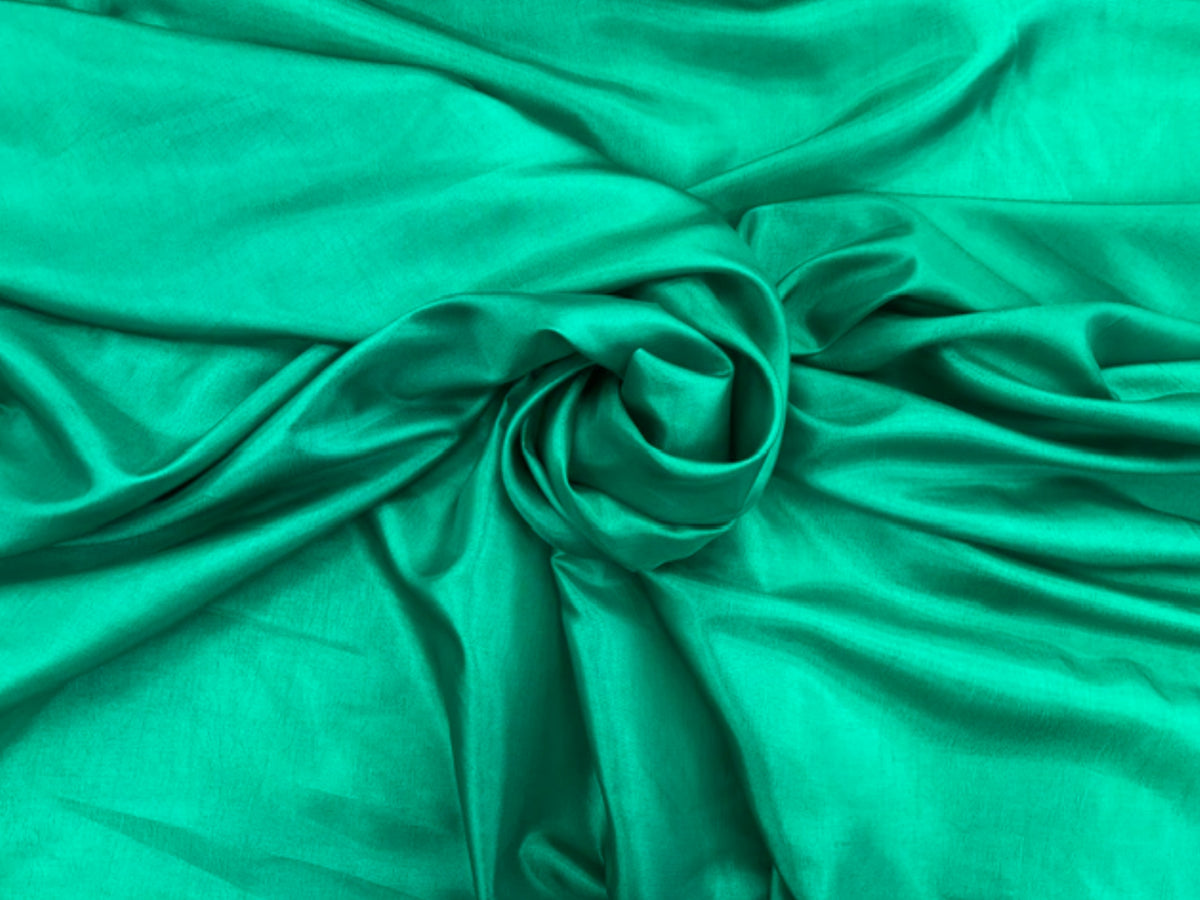 Emerald green taffeta fabric from Cheapfabrics, showcasing smooth, shiny taffeta material ideal for dresses and formal wear.