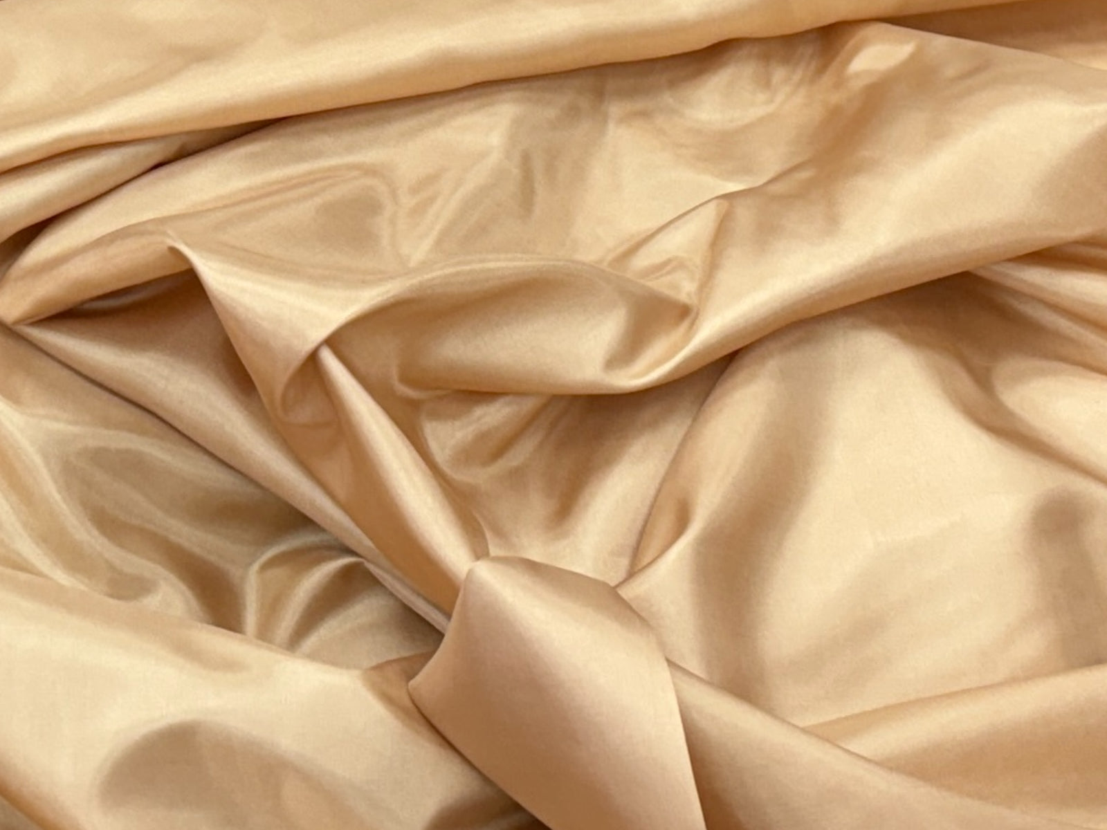 Golden lining fabric from Cheap Fabrics, close-up of smooth, shiny lining material suitable for clothing or accessories.