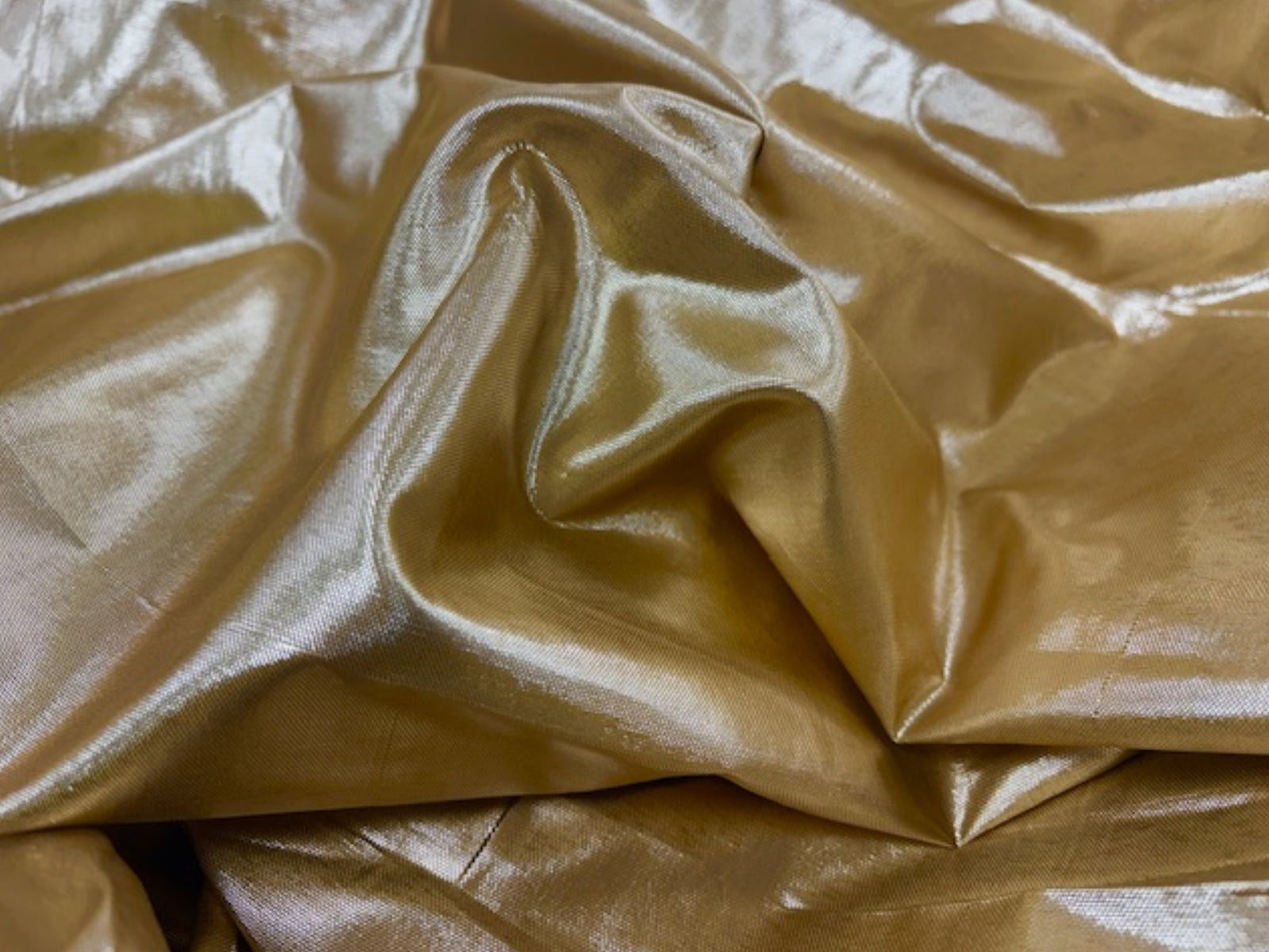 Gold lame fabric from Cheapfabrics, showcasing shiny, smooth, and reflective metallic material suitable for fashion and craft projects.
