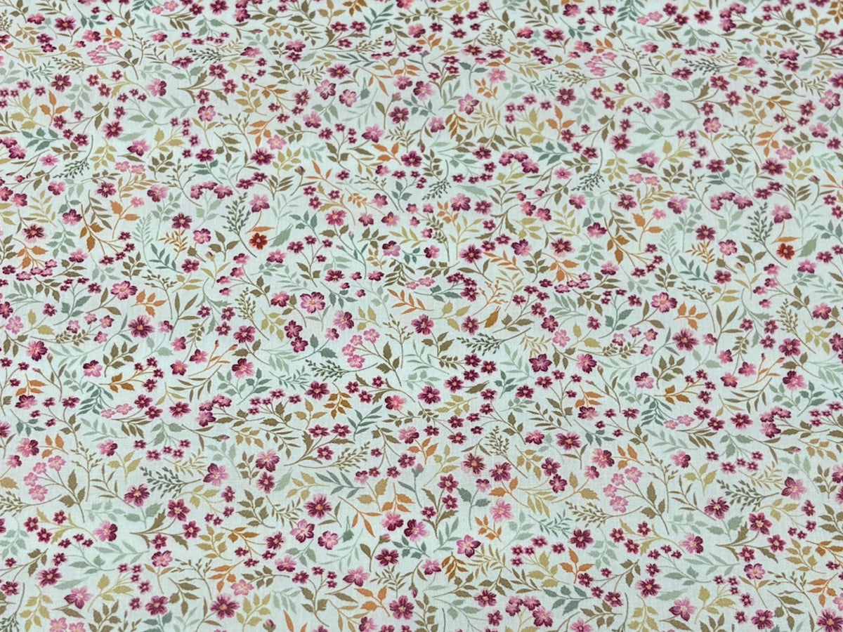 Pink leafy ditsy floral polycotton fabric from Cheap Fabrics, showing a close-up of the colorful floral pattern on soft fabric.