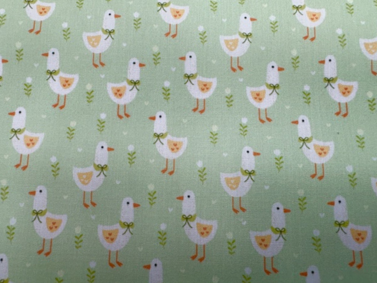 Apple green polycotton fabric with a cute little duck print, ideal for sewing projects and DIY crafts.