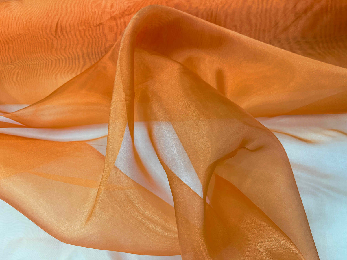 Orange shimmer organza fabric from Cheapfabrics, showcasing its smooth, lightweight, and lustrous texture.