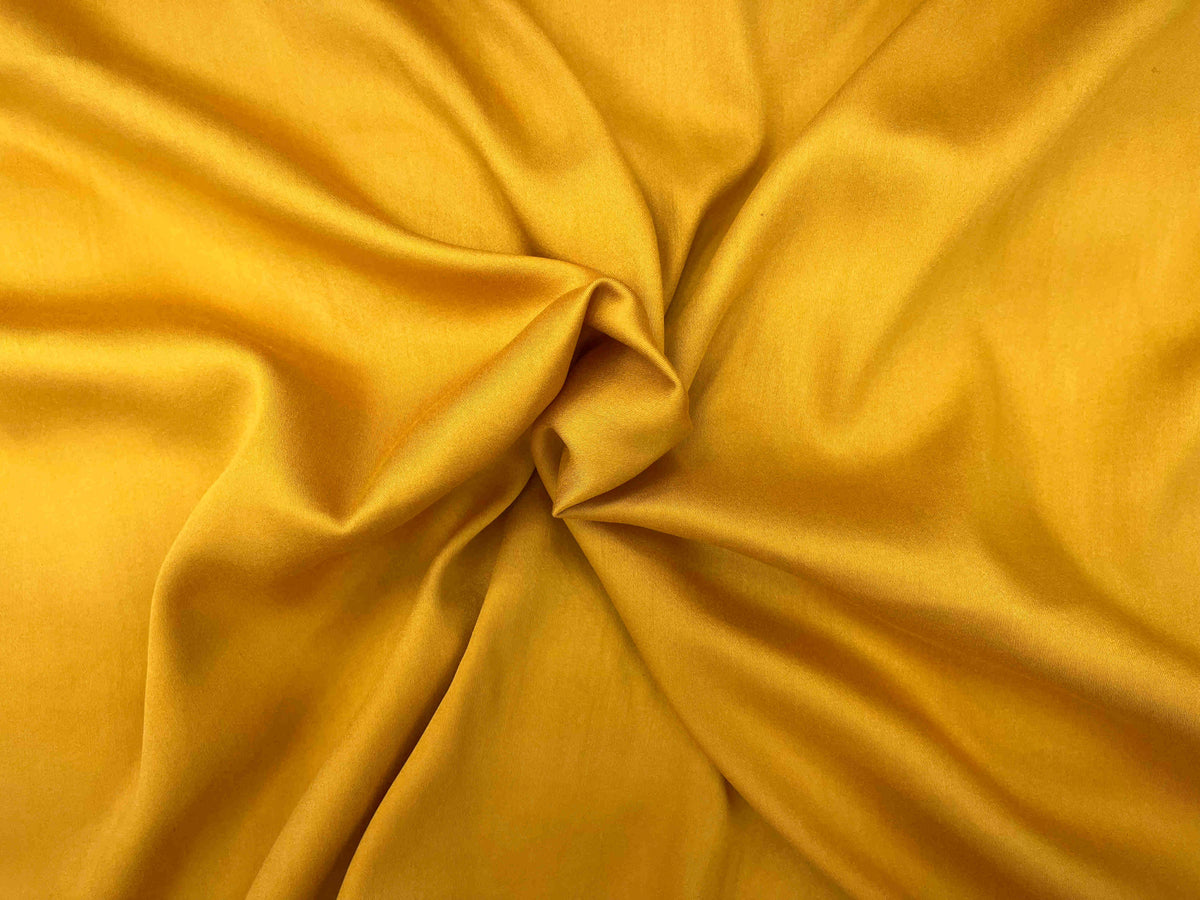 Smooth plain viscose satin fabric in sunflower yellow, showcasing its soft texture and glossy finish from Cheapfabrics.