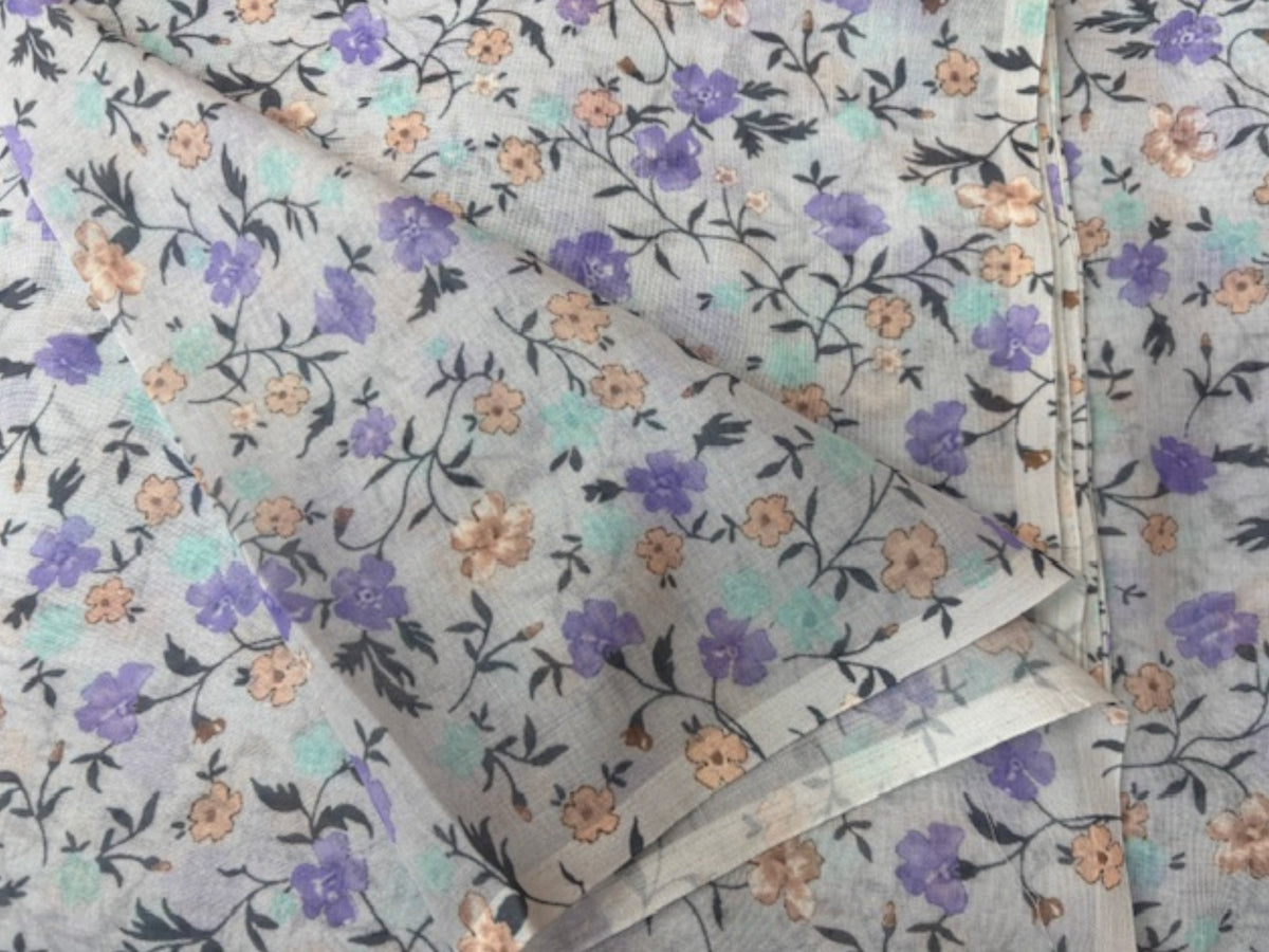Light pastel lilac voile fabric with a delicate floral print, ideal for curtains or clothing, by Cheapfabrics.
