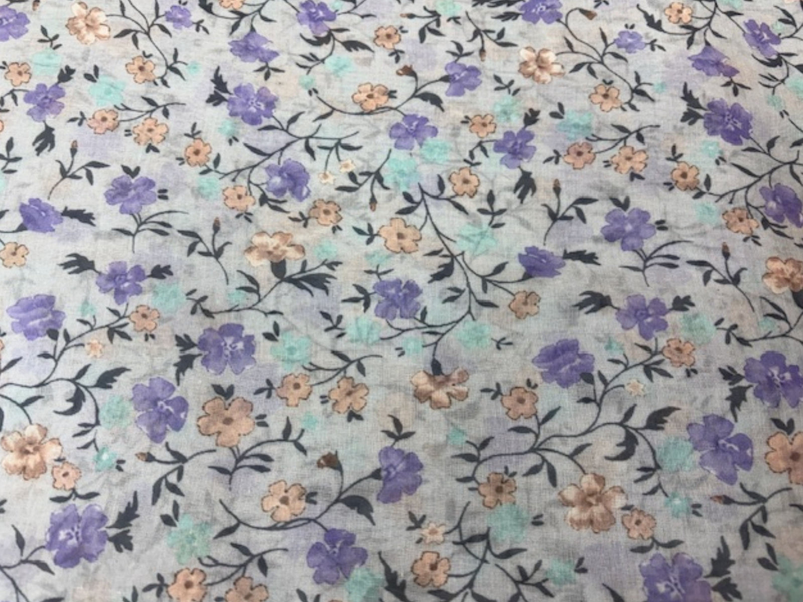 Light pastel lilac voile fabric with a delicate floral print, ideal for curtains or clothing, by Cheapfabrics.