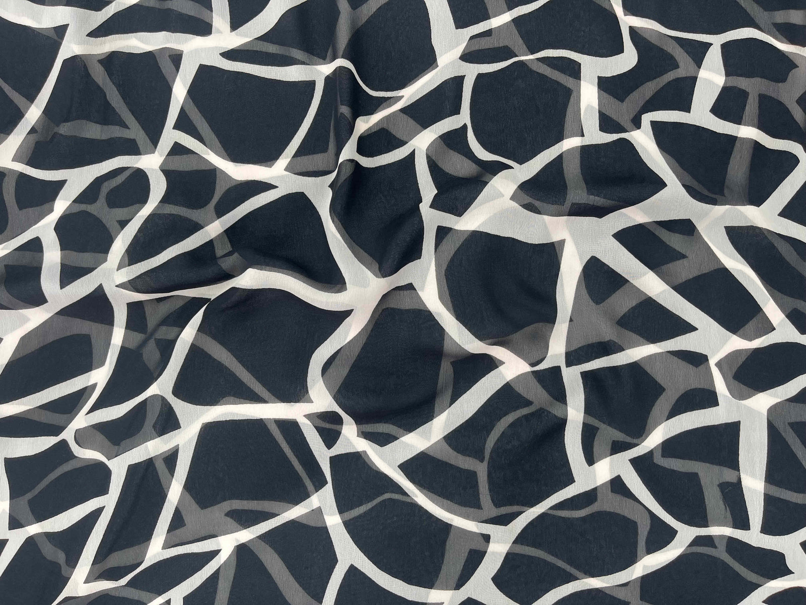 Printed chiffon fabric from Cheap Fabrics Monotone Collection with leopard print design, lightweight and sheer for elegant clothing or crafts.