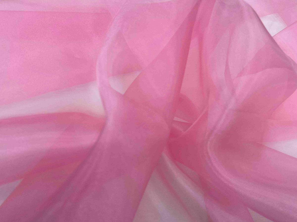 Candy pink shimmer organza fabric by Cheapfabrics, lightweight and sheer with a sparkling, lustrous finish perfect for elegant designs.