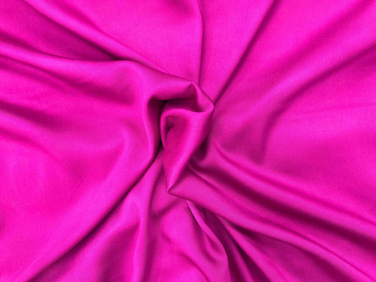 Plain viscose satin fabric in a rich cerise color, showcasing smooth, shiny texture ideal for elegant clothing and accessories.